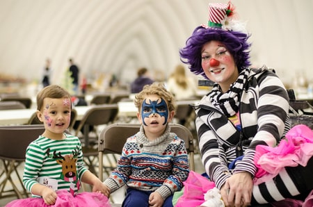 Two children with masks and a woman dressed as a clown in a dome
